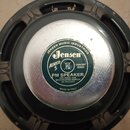 Fotografie znázorňuje zadní část reproduktoru s kovovým magnetem. Na středu je zelený štít s bílými nápisy „JENSEN MUSIC INDUSTRIES“, logem „Jensen“,…