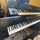 Fotografie zobrazuje dva černé klávesové nástroje značky KORG umístěné nad sebou. Horní nástroj má nápisy MUSIC WORKSTATION a m50, spodní nástroj nes…