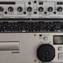 Fotografie zachycuje tři rackové zařízení naskládaná nad sebou. Horní přístroj je kompresor/limiter značky dbx, model 166xs. Prostřední zařízení je M…