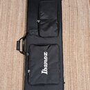 Černý obal na hudební nástroj s dvěma zipovými kapsami. Na spodní kapse je bílý nápis Ibanez. Obal má na boku připevněnou přenosnou rukojeť. Povrch m…