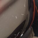 Detailní záběr na zakřivený, vysoce lesklý černý povrch hudebního nástroje. Povrch vykazuje četné drobné škrábance a oděrky. Žádné značky, loga ani n…