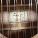 Fotografie zachycuje vnitřek akustické kytary s viditelným štítkem přilepeným k základní desce. Na štítku je uveden nápis Dowina, Antique Series, Pue…