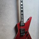 Tmavě červená elektrická kytara s ostře hranatým korpusem a bílým lemováním. Na hlavě hmatníku je bílý nápis Ibanez. Nástroj má dva humbuckery, tři o…