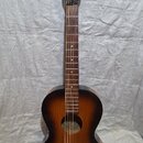Akustická kytara s tmavě hnědým přechodem do žluté barvy (sunburst). Na hlavě je bílý nápis Framus. Nástroj vykazuje známky opotřebení, zejména v pod…