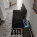 Sada akustických absorbérů z tmavě šedé pěny s vlnovitým povrchem. Vedle nich jsou dva černé plastové stojany a jedna šedá podložka. Soubor doplňuje…