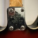 Detail spojení krku s tělem nástroje, zakrytý chromovaným kovovým krytem připevněným čtyřmi šrouby. Na krytu je vyražen nápis STEEL ADJUSTABLE NECK,…
