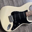 Krémová elektrická kytara s černým pickguardem a hnedým hmatníkem. Nástroj má tři snímače typu single-coil, tři ovládací knofíky a jeden přepínač. Na…