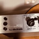 Detailní pohled na přední panel stříbrného efektového procesoru. Na zařízení je uveden nápis M350 EFFECT | REVERB PROCESSOR a logo t.c. electronic. P…