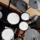 Elektronická bicí souprava značky Alesis. Na module je nápis Alesis a Crimson 1, na bubnech jsou viditelná loga Alesis. Souprava obsahuje čtyři bílé…