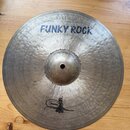 Kovový činel s kovaným povrchem a viditelnými rýhami. V horní části je modrý nápis FUNKY ROCK a nad ním menší text 14"/35cm a nečitelný podpis. V dol…