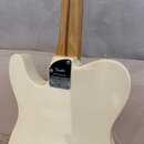Zadní strana elektrické kytary v krémové barvě s krkem z jasného dřeva. Na spojení krku a těla je kovový štít s nápisy „Fender“ a „AMERICAN PROFESSIO…