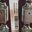 Detail zadní strany hlavy kytary v tmavě červené barvě s chromovanými ladicími kolíky. Na bílé nálepce je uveden text GRETSCH G5425 Jet Club, kód HN1…