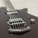 Detailní pohled na tmavě hnědou elektrokitaru s viditnou strukturou dřeva. Nástroj má dva humbuckery, chromovaný most a stop-bar strunovník. Na těle…