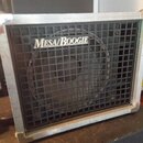 Kytarový kombozesilovač s černou síťovkou a stříbrným kovovým rámem. Na síťovce je umístěno bílé logo MESA/BOOGIE. Povrch kovového rámu vykazuje znám…