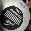 Fotografie zachycuje zadní stranu kulatého kovového reproduktoru stříbrné barvy. Na černé nálepce je uveden nápis ARV-104-04/4, 4 Ohm a logo acoustic…