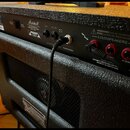 Zadní strana černého kytarového komba s texturovaným povrchem. Na ovládacím panelu je logo Marshall a nápisy SEND, RETURN, FOOTSWITCH, LOUDSPEAKERS,…