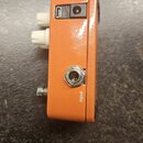 Fotografie zachycuje boční stranu oranžového efekt pedálu. V horní části jsou umístěny USB port a konektor pro napájení, ve spodní části je vstupní j…