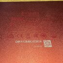 Detail spodní strany červeného zařízení s texturovaným povrchem. Je zde vidět logo Focusrite, značka CE a sériové číslo D8FATZM9C0CBC8 spolu s QR kód…