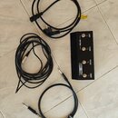 Černý ovládací pedál s nápisy LEAD, CLEAN, REVERB a BOOST, u kterého je umístěno logo IRON HEART. K pedálu patří tři černé kabely: napájecí kabel s e…