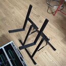 Černý kovový stojan v tvaru X s dvěma opornými tyčemi. V levém dolním rohu je vidět část modulu s nápisy A-100 ANALOG MODULAR SYSTEM a DOEPFER. Povrc…