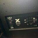 Zadní panel černého aktivního subwooferu s textem X SUB 118 SA PROCESSED ACTIVE SUBWOOFER a logem FBT. Panel obsahuje ovládací prvky jako volič LEV,…