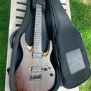 Elektrická kytara s tmavým dřevěným povrchem a vyřezanými vložkami z lehčího dřeva na horní dece. Nástroj má dva humbuckery, jeden ovládací knoflík a…