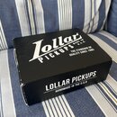 Černá papírová krabice s bílými nápisy. Na horní i boční straně je uveden název LOLLAR PICKUPS a text HANDMADE IN THE U.S.A. Horní strana obsahuje dá…