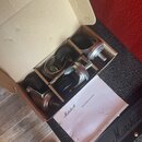 V kartonové krabici jsou čtyři černé kolečka s kovovými úchyty a šrouby. Vedle nich je přiložen bílý papír s nápisy Marshall a Castor fitting instruc…