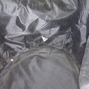 Fotografie zachycuje vnitřek černé textilní tašky nebo obalu. Materiál je zmačkaný a v centrální části je viditelná trhlina v látce. Žádné značky ani…