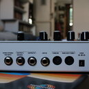 Zadní strana bílého efekt pedálu s několika konektory. Nad vstupy jsou nápisy MONO/STEREO TRS INPUT, OUTPUT L (MONO), OUTPUT R, EXP IN, MIDI IN, MIDI…