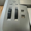 Detailní pohled na ovládací panel stříbřitého klávesového nástroje. Jsou zde vidět dvě černé ovládací kolečka s nápisy PITCH BEND a MODULATION, dvě č…