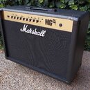 Kytarový kombozesilovač značky Marshall v černé barvě s gold panelem. Na přední mřížce je bílé logo Marshall a na ovládacím panelu nápis MG 100FX. Ho…