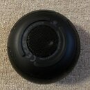 Černý kulatý reproduktor s mřížkou v centru. Na horní části je nápis OPEA 2 BY ARTIPHON a logo CE. Povrch je matný, v horní části jsou vidět drobné p…