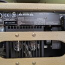 Zadní panel kytarového komba v béžovém potahu. Na černém kovovém panelu jsou vidět konektory s popisky PRE AMP OUT, POWER AMP IN, FOOT SWITCH, MAIN S…