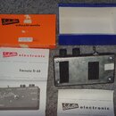 Fotografie zobrazuje efekt Tremolo Tr 68 v kovovém šedém provedení s dvěma černými ovládacími knoflíky a přepínačem. Na přístroji je nápis „Schaller…