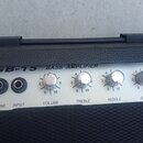Detail ovládacího panelu basového komba v černém texturovaném provedení. Na stříbrném panelu je nápis GB-15 BASS AMPLIFIER a čtyři ovládací knoflíky…