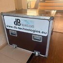 Hnědý transportní case s hliníkovými hranami a kovovými rohy. Na přední straně je bílý štítek s modrým logem dB TECHNOLOGIES a nápisem www.db-technol…
