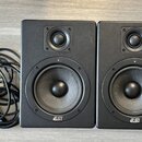 Dva černé studiové monitory s logem ESI v dolní části. Každý reproduktor obsahuje jeden výšký a jeden středně-nízký měnič. Vedle monitorů je srolovan…