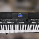 Černý digitální klavír s bílými a černými klávesami. Na horní části je uprostřed logo YAMAHA, displej a po stranách dva reproduktory. V pravém dolním…