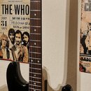Černá elektrická kytara s bílým pickguardem a hnědým hnedým hmatníkem. Na hlavě nástroje je viditelné logo Squier. Kytara má tři bílé snímače typu si…