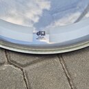 Detail bílé, poloprůhledné bubny s nápisem heads a logem DW. Pod logem je text COATED/CLEAR HEAD BY REMO U.S.A. Povrch vykazuje mírné znečištění a od…