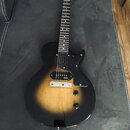 Elektrická kytara s trupem v černo-žlutém sunburst provedení a černým pickguardem. Na hlavě hmatníku je viditelné logo "Epiphone". Nástroj má dva sní…