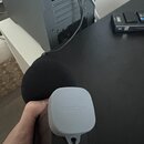 Ruka drží přenosný digitální záznamník v černém pouzdře. Na šedém plastovém krytu je vyražen nápis ZOOM. Zařízení má nasazenou černou větrnou clonu.
