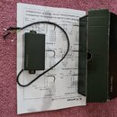 Černý plastový box s elektronikou a připojenými vodiči, položený na papírovém návodu k zapojení. Na boku boxu je bílý nápis R.M.pickups. Vedle zaříze…