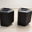 Dva černé reproduktory s plastovým korpusem a mřížkami v přední části. Horní strana každého reproduktoru obsahuje úchopovou rukojeť. Na viditelných č…