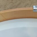 Detailní pohled na horní hranu dřevěného korpusu bubnu světlé barvy. Na pravé straně je vidět kovový chromovaný lug. Povrch dřeva vykazuje v levé čás…