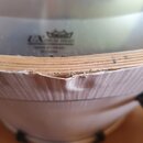 Detailní pohled na horní hranu bubnu s napnutým bílým blanou. Na bláně je černý nápis UX DRUM HEAD, nad ním logo REMO a pod ním drobný nečitelný text…