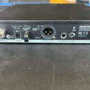 Černý bezdrátový přijímač značky SHURE s nápisem SLX4 RECEIVER a webovou adresou www.shure.com. Na zadním panelu jsou vidět konektory pro antény, nap…