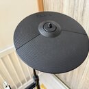 Černý gumový pad elektronického činelu s koncentrickými drážkami. Na horní části je vyražen nápis Roland. Povrch vykazuje mírné známky používání v po…