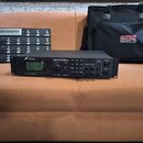 Na fotografii jsou tři předměty: černý rackový procesor, černý MIDI kontrolér a černá přepravní taška. Procesor nese nápisy FRACTAL AUDIO SYSTEMS, Ax…
